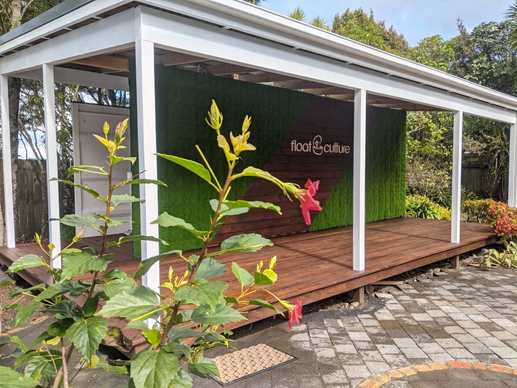 The Float Club Titirangi building with its green wall and timber deck, framed by native planting